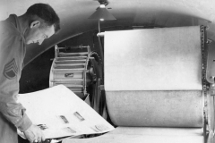 Bernice inspects prints from dryer. France. Aug 1944.