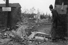 bob peaks through shell hole into war torn German civilian cemetery. G